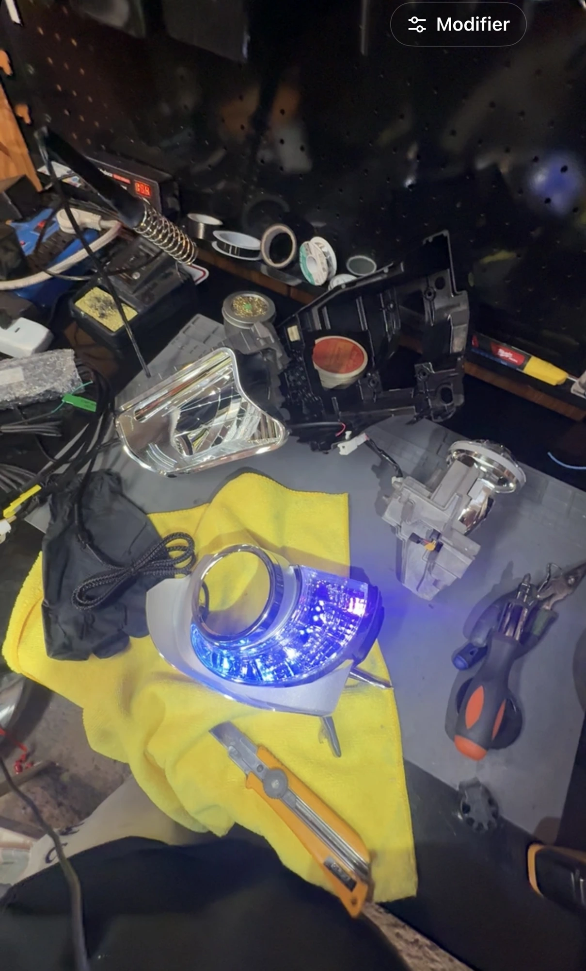 Infiniti Q50 headlight components laid out during bench work